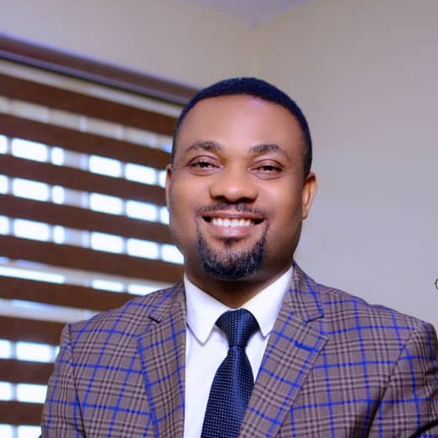 Pastor Israel Kayode-Oloje seated, in a blue check suit